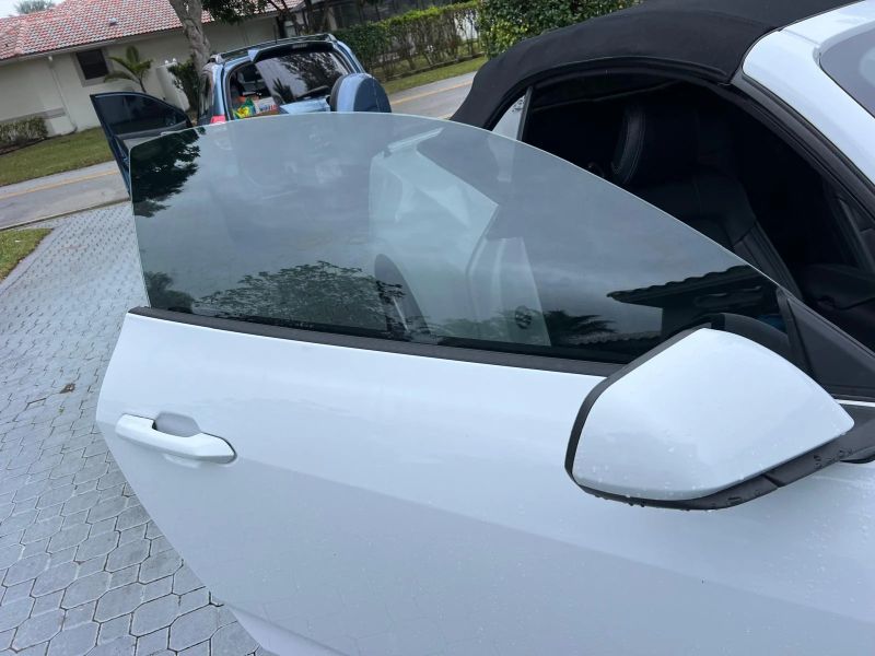 Close-up of freshly tinted door glass on a white Mustang reflecting trees