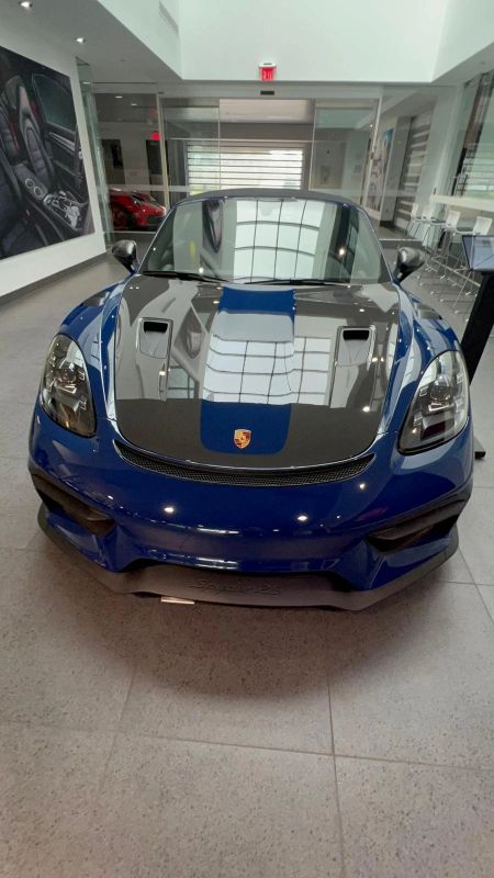 Blue Porsche 718 Spyder RS with carbon hood, front view in a showroom