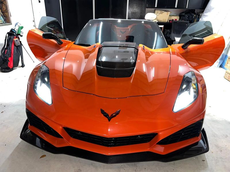 Orange Corvette ZR1 convertible in a garage with both doors open showing tinted side glass